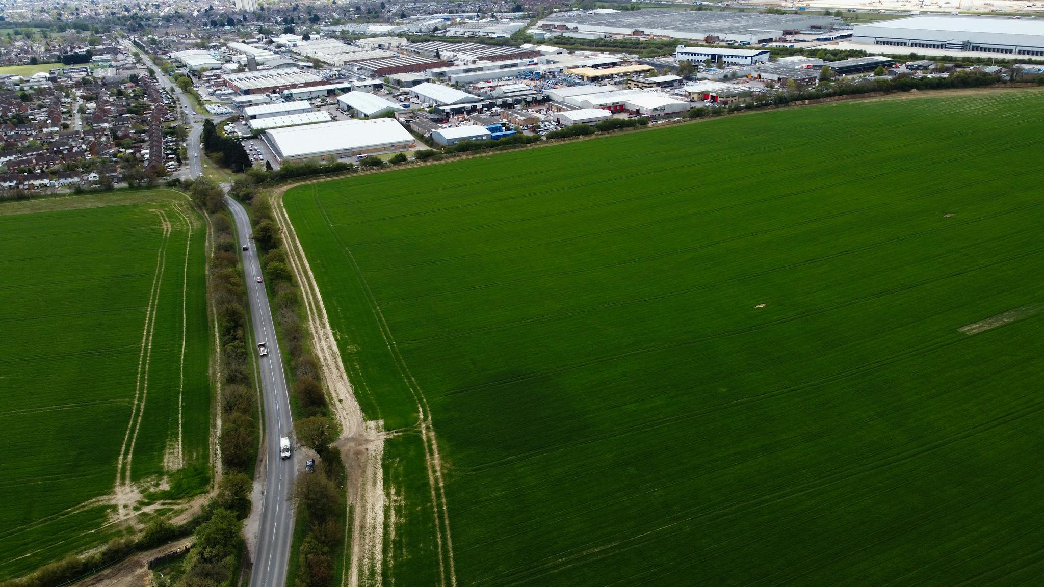 Drone shot of lush green fields and industrial areas in Central Bedfordshire, England.