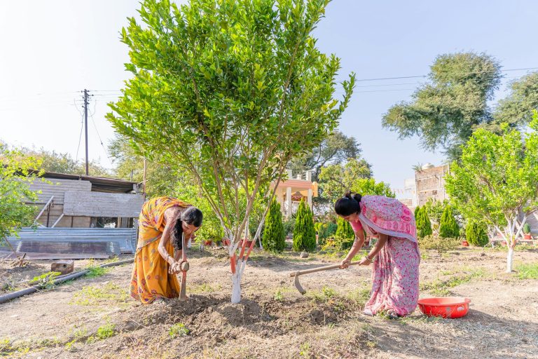 Two Indian women farming in a countryside setting, illustrating traditional agriculture.